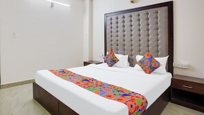 A neatly made bed with a colorful bed runner, a tufted headboard, and two nightstands with drawers. - FabHotel Leo Grand (Anekal)