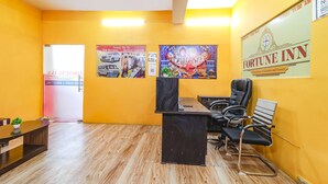 A hotel reception area with a wooden floor, a reception desk, black leather chairs, and a large 'Fortune Inn' sign on the wall. - FabExpress Swarn Fortune inn (Patna)