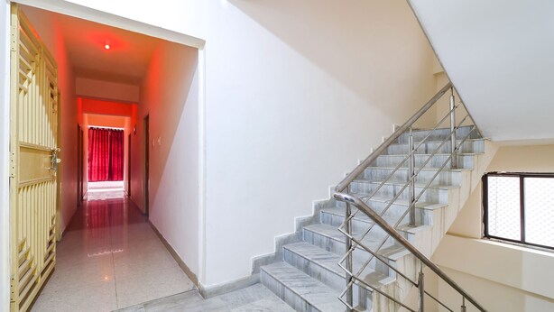 A modern interior with a marble staircase, a hallway with a red curtain, and a yellow gate. - FabExpress Swarn Fortune inn (Patna)