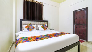 A bed with a white mattress and a colorful geometric-patterned bedspread. - FabExpress Swarn Fortune inn (Patna)
