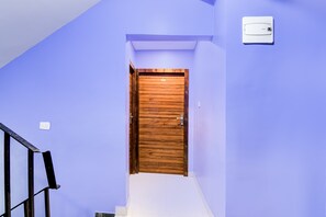A wooden door at the top of a staircase in a room with light blue walls. - FabHotel Shiva Inn (Barasat)