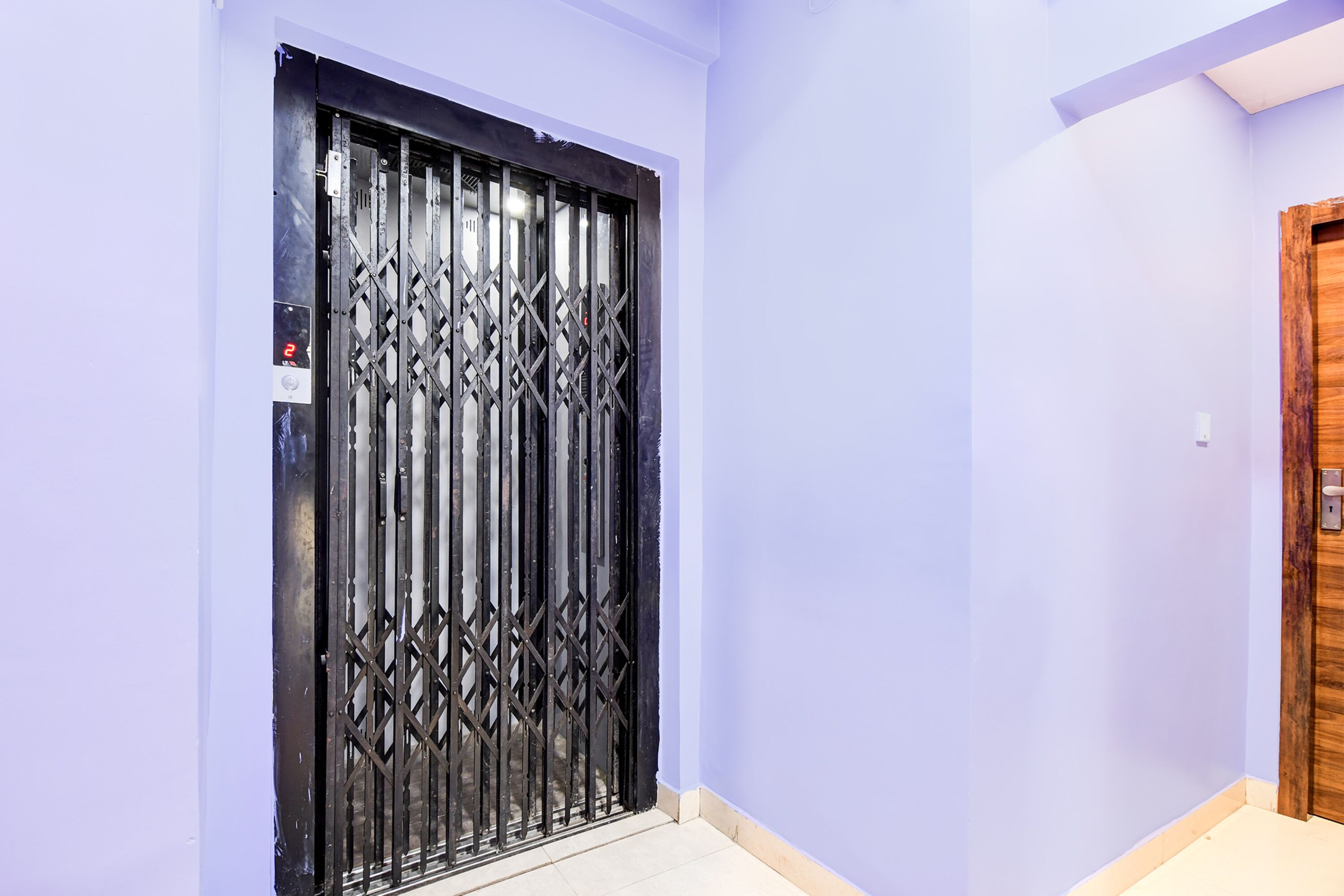 A hallway with a metal gate and a wooden door.