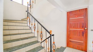 Una escalera con barandillas de metal ornamentadas y una puerta roja con rayas horizontales.