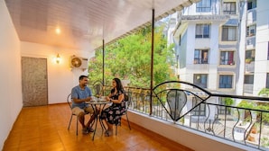 Un balcón con suelo de baldosas y barandilla, con vistas a una zona residencial con edificios y vegetación.
