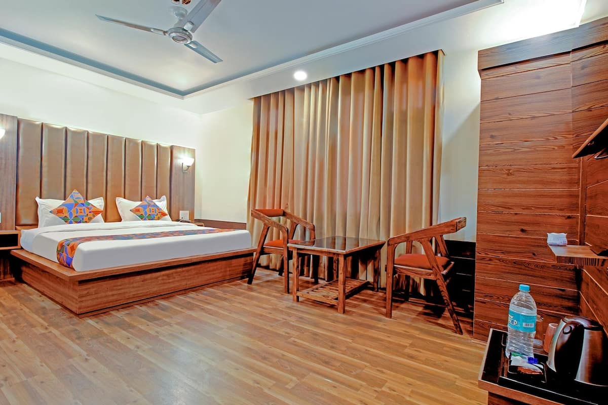 Quarto de hotel com cama de madeira, uma escrivaninha e uma cadeira.