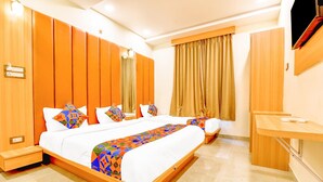 A hotel room with a large bed, a desk, and a wardrobe. - FabExpress Mewar Shine (Udaipur)