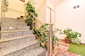 Una escalera de granito con barandillas metálicas y plantas en macetas.