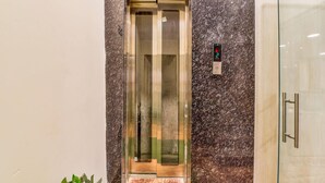 An elevator with a digital display and a marble wall. - FabExpress Mewar Shine (Udaipur)
