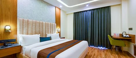 A hotel room with a large bed, a desk with a chair, a ceiling fan, and a window with curtains.