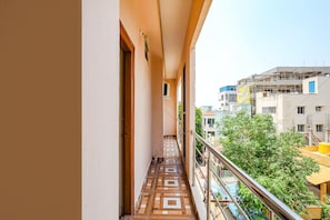 A narrow balcony with patterned flooring, a metal railing, and a view of surrounding buildings. - FabHotel Seven Inn Home Stay (Tirupati)