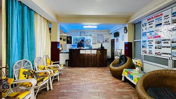 A reception area with a counter, chairs, and a bulletin board with maps. - FabHotel Palbheu (Gangtok)