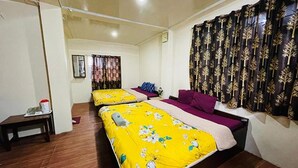 A hotel room with two beds, a small table, and a curtain with a leaf pattern. - FabHotel Palbheu (Gangtok)