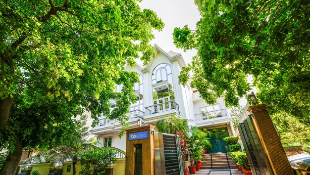 A hotel entrance with a gated driveway, potted plants, and a staircase leading to the entrance.