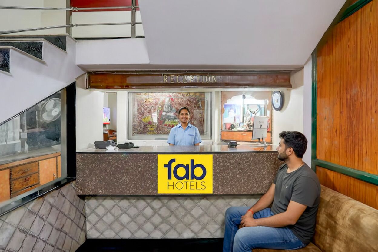 A reception desk with a sign for 'fab hotels' and a man sitting on a couch.