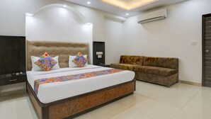A modern bedroom with a large bed, a sofa, a ceiling fan, and an air conditioning unit. - FabHotel Classic (Bhopal)