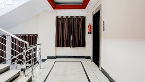 A hotel lobby with a staircase, a fire extinguisher, and a door. - FabHotel Classic (Bhopal)