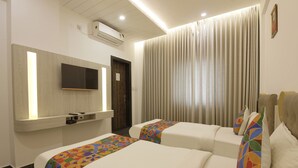 A hotel room with two beds, a TV mounted on the wall, and a window with curtains. - FabHotel Silver Key (Anekal)