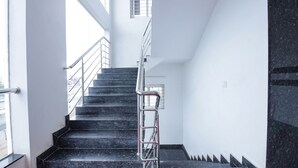 A staircase with black marble steps and metal railings, leading to an upper floor in a building with white walls and a window. - FabHotel Silver Key (Anekal)