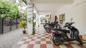 A corridor with tiled flooring, potted plants, and parked scooters.