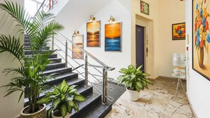 A staircase with metal railings, potted plants, and framed artwork on the walls.