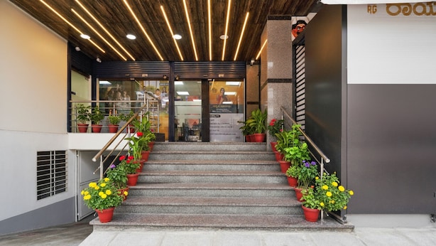 A staircase leading to a building entrance with potted plants on either side. - FabHotel Royal Grand (Bengaluru)