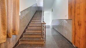 A staircase with a metal handrail, marble steps, and a wooden panel on the right. - FabHotel Royal Grand (Bengaluru)