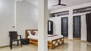 A bedroom with a bed, a chair, a wardrobe, and a ceiling fan. - FabHotel Galaxy Airport Inn (Pune)