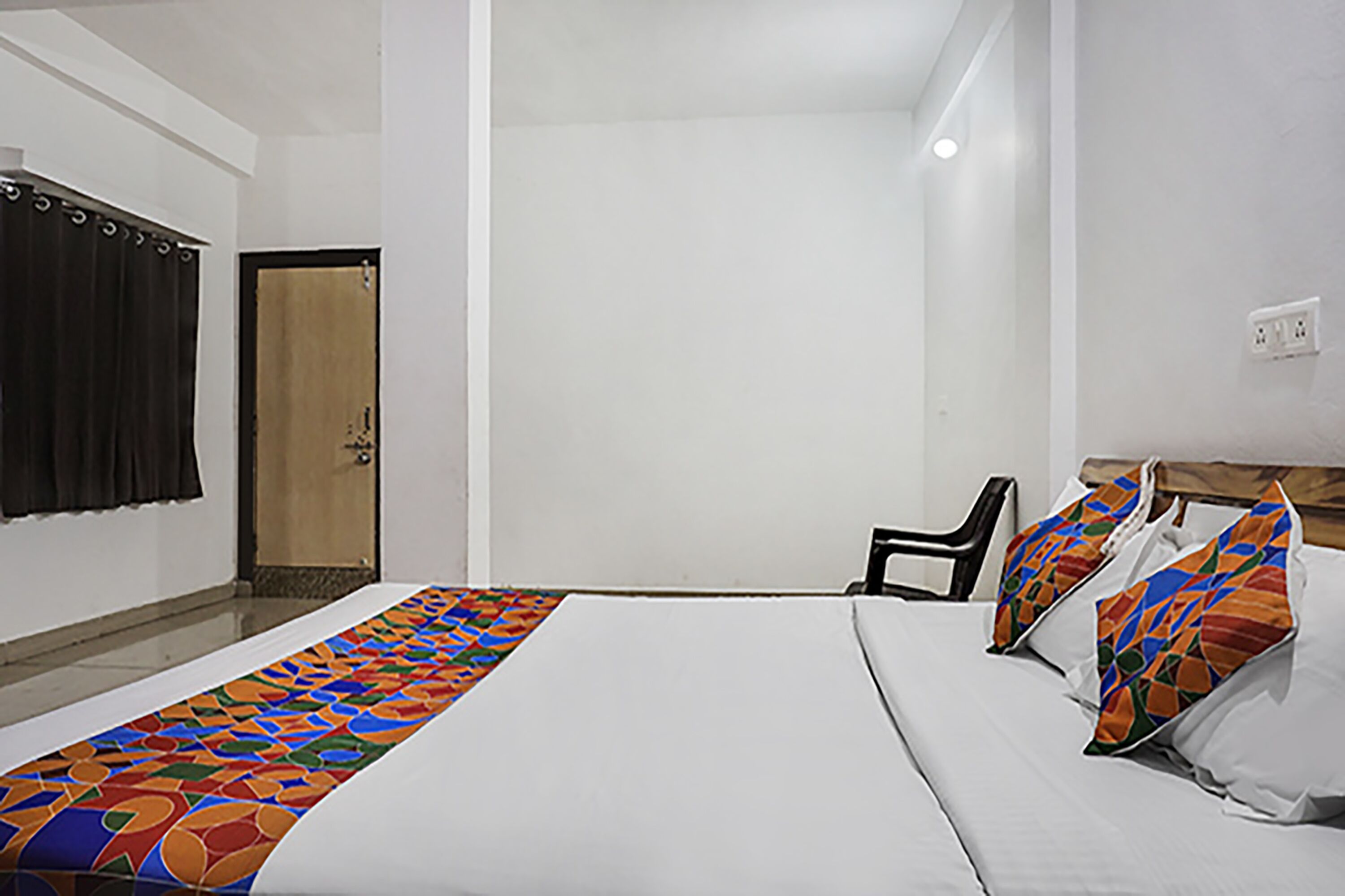 Une chambre d’hôtel avec un lit, une chaise et une porte.