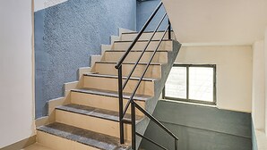 A staircase with beige steps and black railings, leading to a landing with a window. - FabHotel Galaxy Airport Inn (Pune)