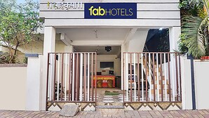 The entrance to a hotel with a gated driveway and a reception desk visible inside. - FabHotel Galaxy Airport Inn (Pune)