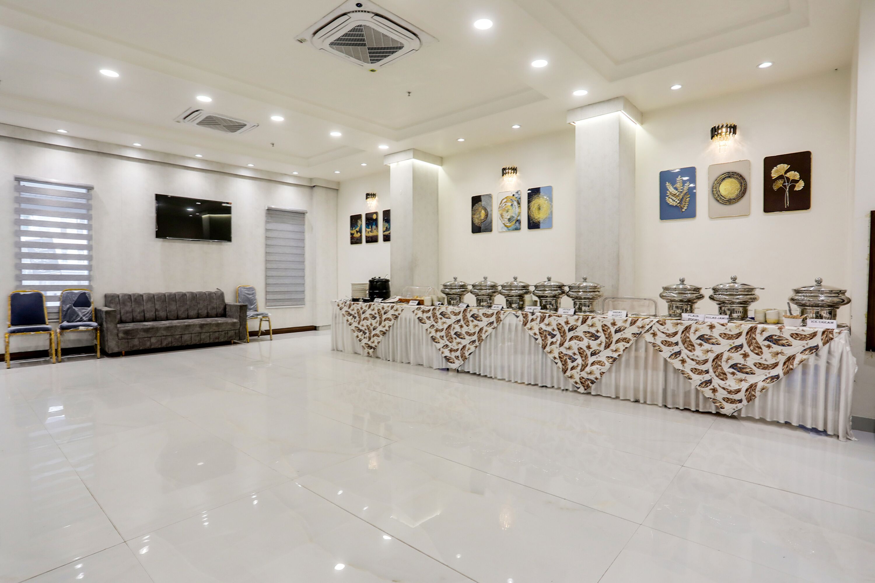 A spacious room with a long table covered with patterned tablecloths, a sofa, and chairs.