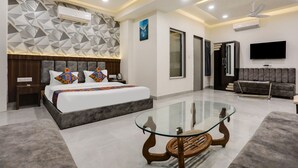 Une chambre d’hôtel moderne avec un grand lit, une table basse en verre, un canapé et un téléviseur à écran plat.