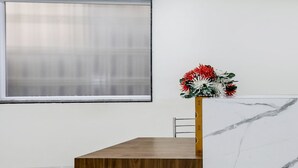 A reception desk with a wooden finish, a marble-patterned counter, and a floral arrangement. - FabHotel Mansarovar Inn (Raipur)