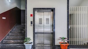 An elevator with a control panel, a staircase, and two potted plants. - FabHotel Mansarovar Inn (Raipur)