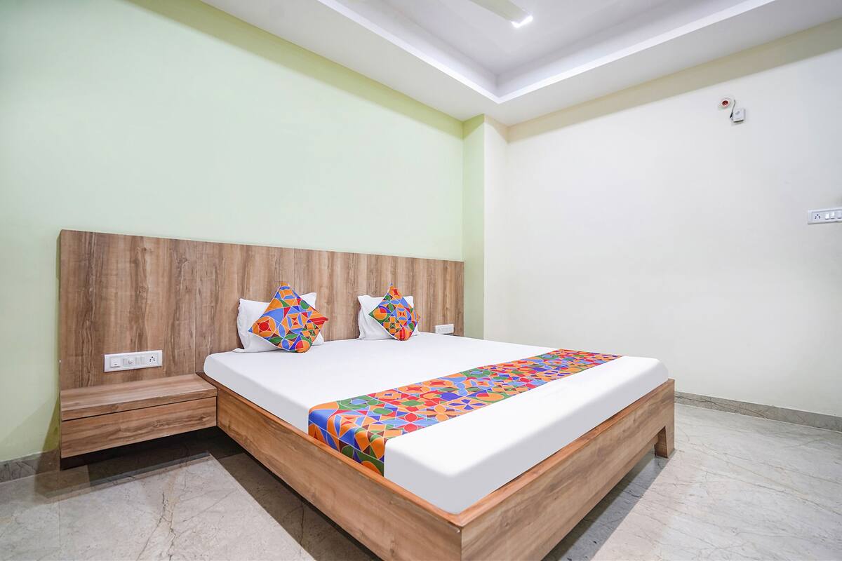 A neatly made bed with a wooden headboard, a colorful bedspread, and two decorative pillows.