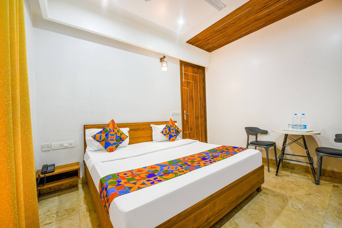 Ein Hotelzimmer mit einem Bett, einem kleinen Tisch mit Stühlen, einer Holzbalkendecke und einer Tür.