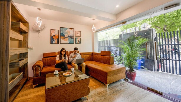 A modern living room with a sofa, coffee table, and artwork on the wall. - FabHotel Nyra Residency (Gurugram)