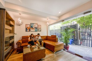 A modern living room with a sofa, coffee table, and artwork on the wall. - FabHotel Nyra Residency (Gurugram)