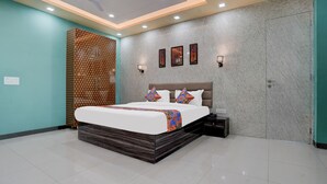 A modern bedroom with a large bed, a nightstand, a wall-mounted TV, and a ceiling fan. - FabHotel Sky - Nr. Sapphire 83 Mall, Manesar (Gurugram)