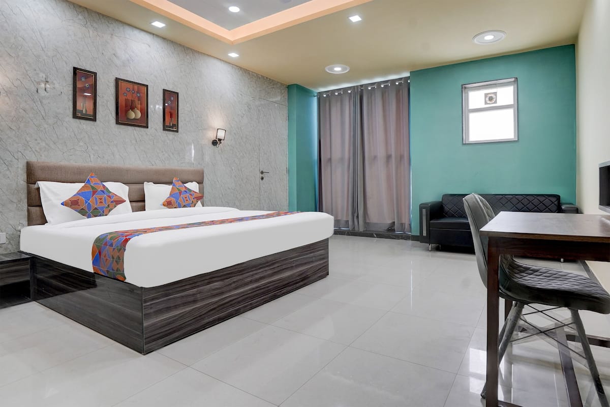 A modern hotel room with a large bed, a dining table, and a sofa.