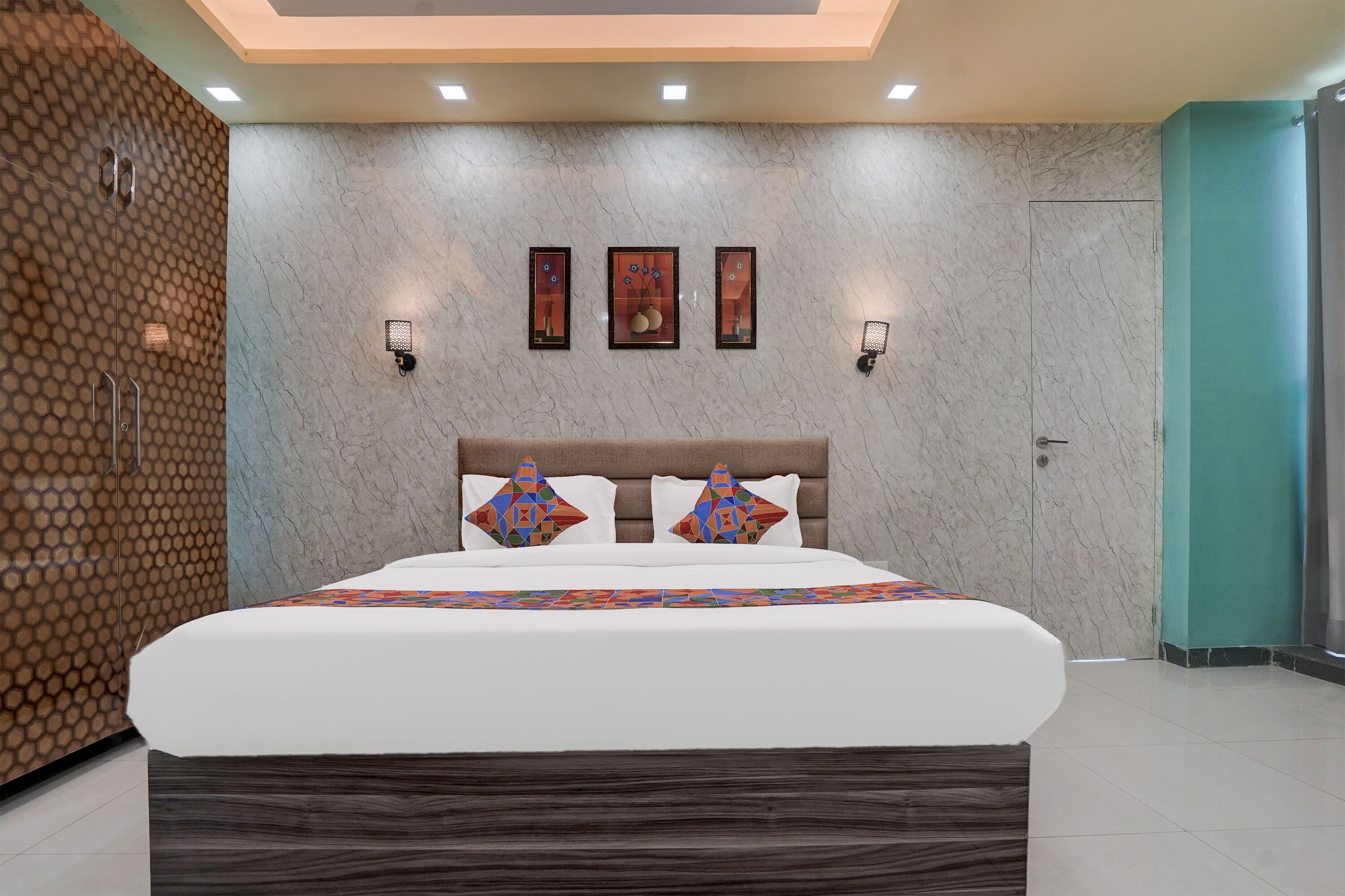 A modern bedroom with a large bed, a headboard, and a wall-mounted light fixture.