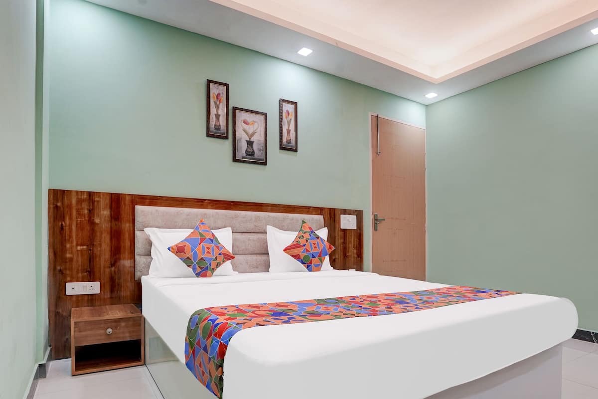 A neatly made bed with a patterned bedspread, a wooden headboard, and a small bedside table with a drawer.