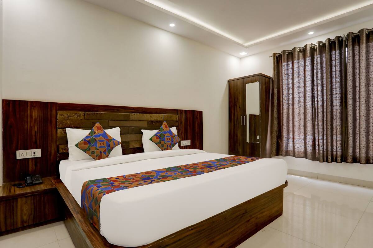 A neatly made bed with a patterned bedspread, a wooden headboard, and two pillows with geometric designs.