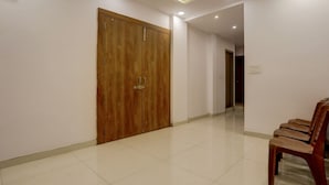 Un pasillo con puerta de madera, un banco y suelo de baldosas.