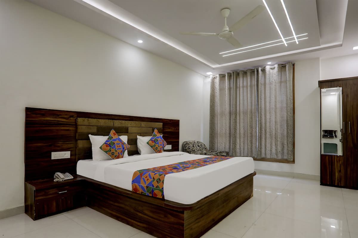 A modern bedroom with a wooden headboard, a bed with patterned pillows, a bedside phone, and a ceiling fan.