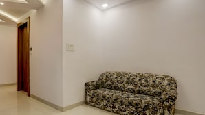 Una habitación con un sofá estampado, una puerta de madera y un interruptor de luz en la pared.