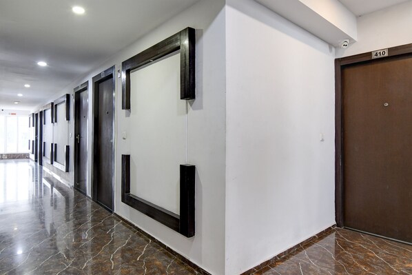 A hallway with a marble floor, a large mirror, and a door marked with the number 410. - FabHotel Prime Eco Park (Barasat)
