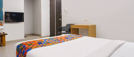 Une chambre d’hôtel avec un lit, un bureau, une chaise, une télévision et une porte.