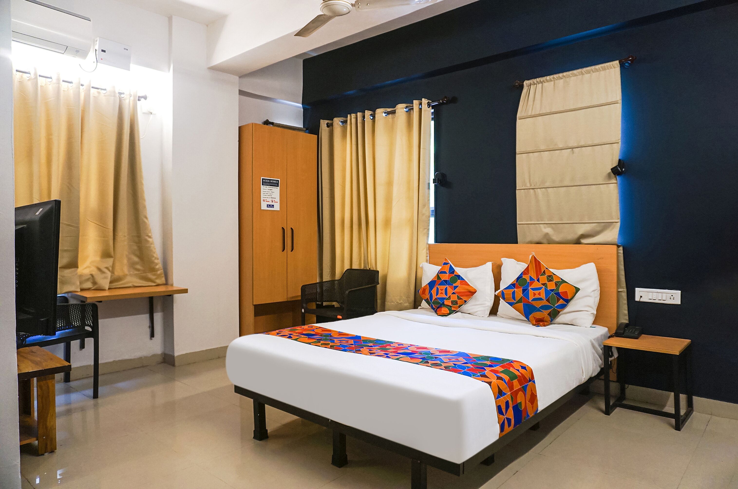 A hotel room with a bed, a desk, a chair, a wardrobe, and a television.