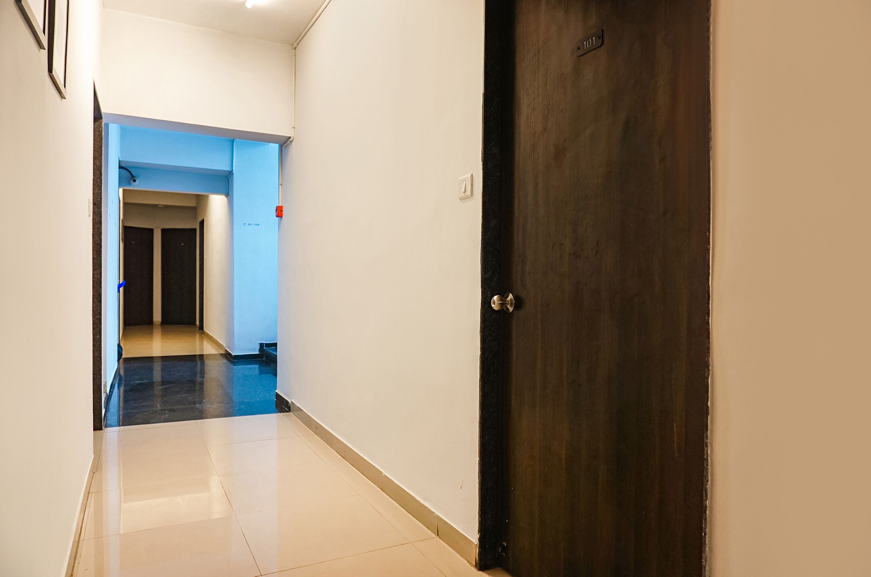 A hallway with a dark wooden door and a blue-lit elevator.